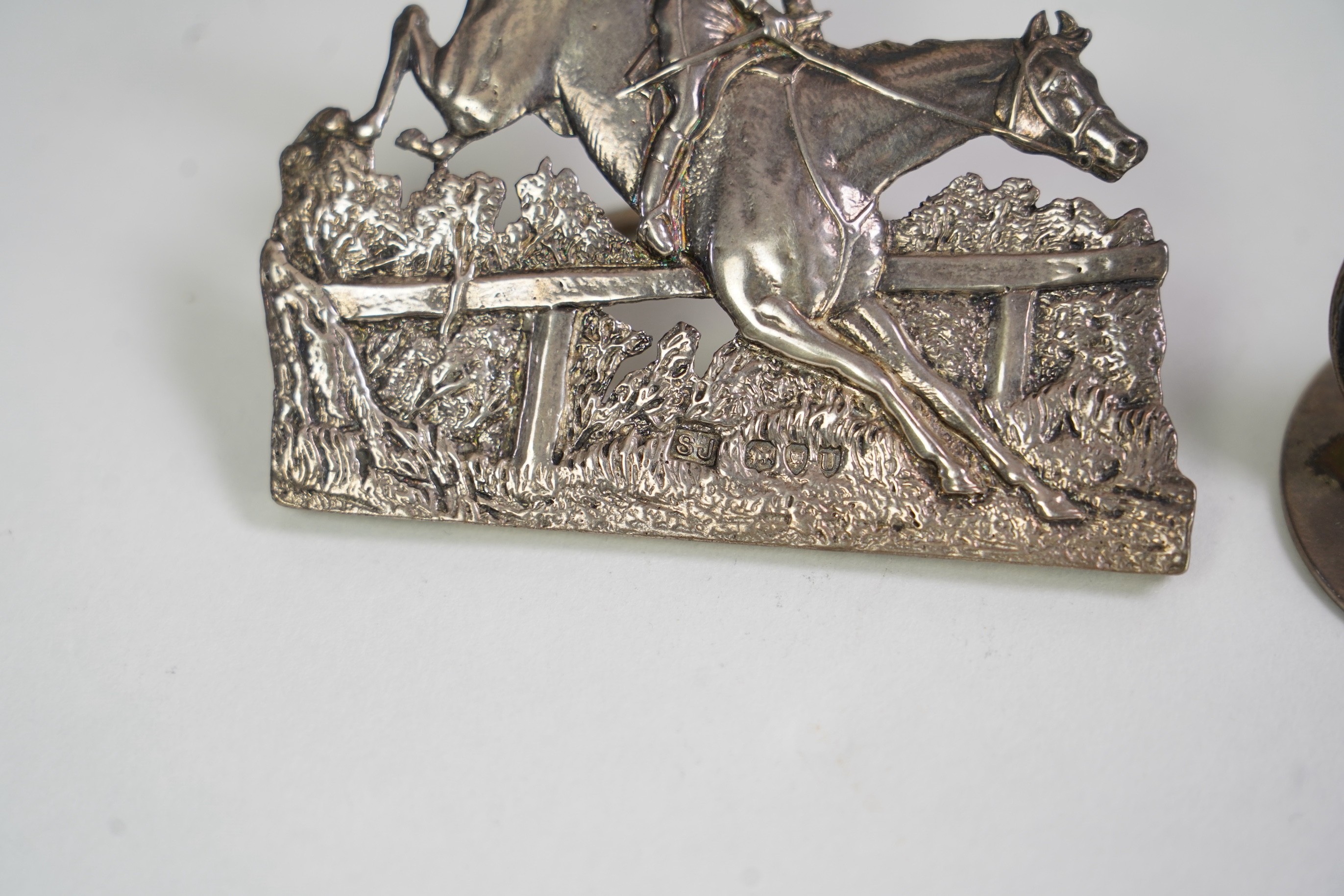 A pair of late Victorian silver menu holders, each modelled as a horse and rider leaping a fence, by Samuel Jacob, London 1894/5, height 66mm, together with a pair of Edwardian silver and enamel menu holders, each decora